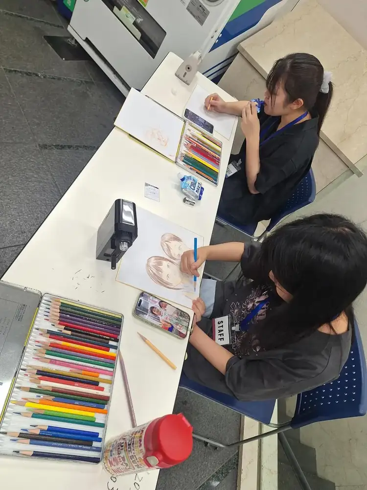 学生が来場者の似顔絵を制作している様子