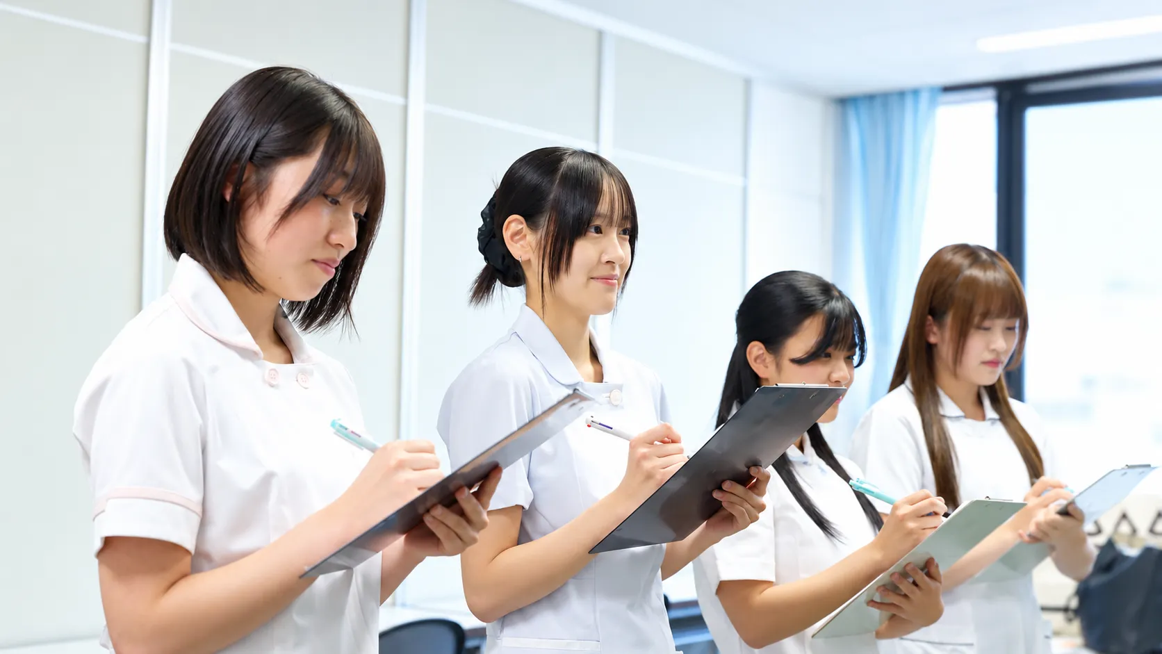 4人の学生がクリップボードを持って実習に取り組む様子